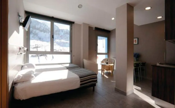 Ski holidays in Pas de la Casa Andorra. A photo showing a large bedroom at Aparthotel Olimpiades with a direct view of the slopes and mountains.