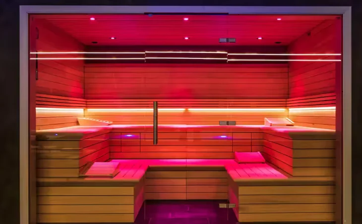 Ski holidays Soldeu, Andorra. A picture of a sauna in Hotel Piolets illuminated by pink lights.