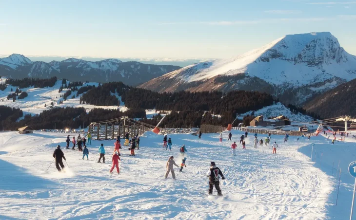 Ski holidays France - A group of beginner skiers on a blue piste in Avoriaz, France. Skiers are viewed from behind and mountains are in the background.