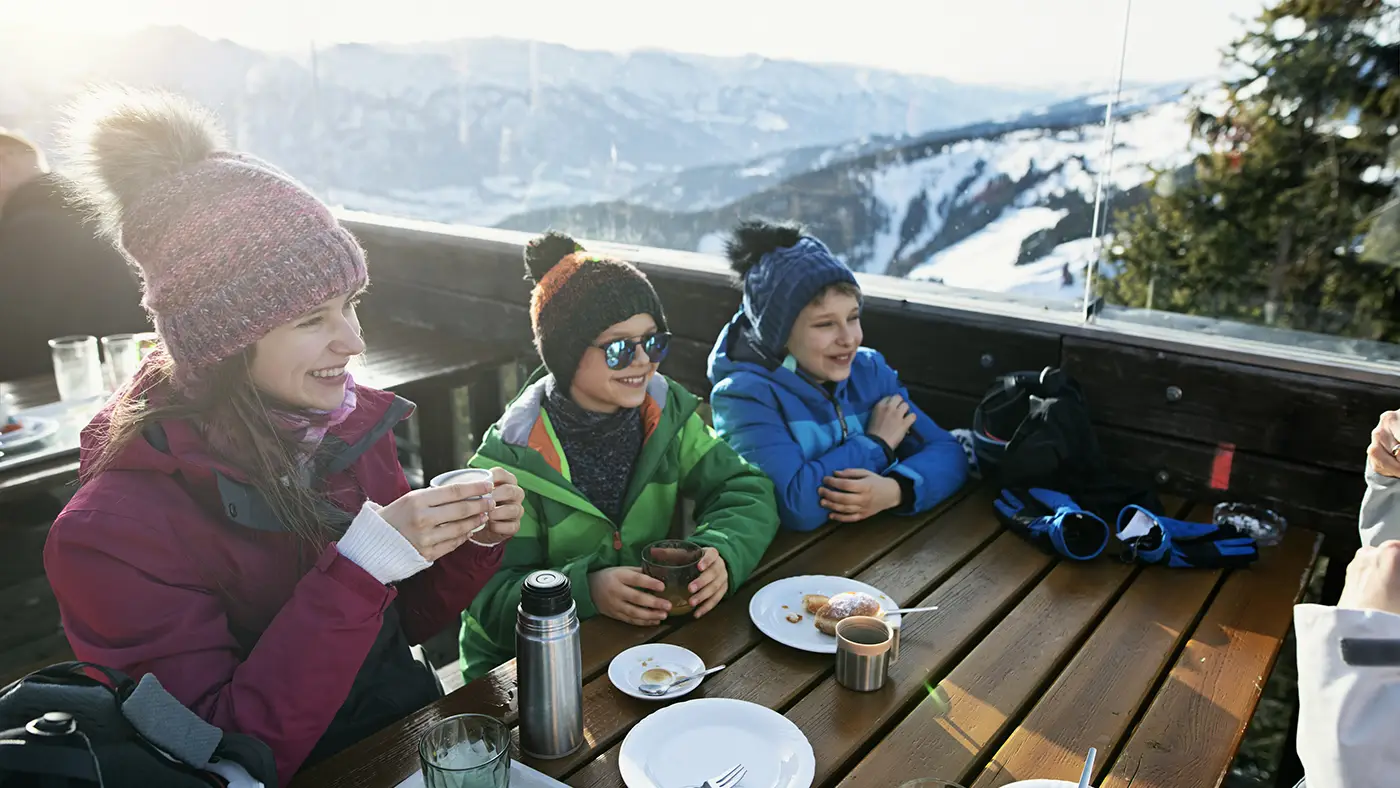 A mother and young family enjoy food and drink after a day's skiing