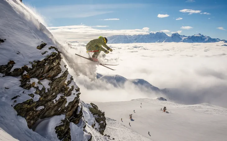An off-piste skier flies of the edge of a rock at high altitude