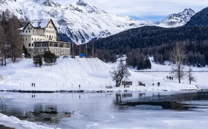 A view across a frozen lake with a grand building in the mid distance in the exclusive Swiss ski resort of St Moritz