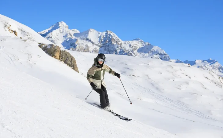 A skier exploring the ski terrain of Val D'Isere and Tignes on their ski holiday in France. It's a beautiful sunny day.